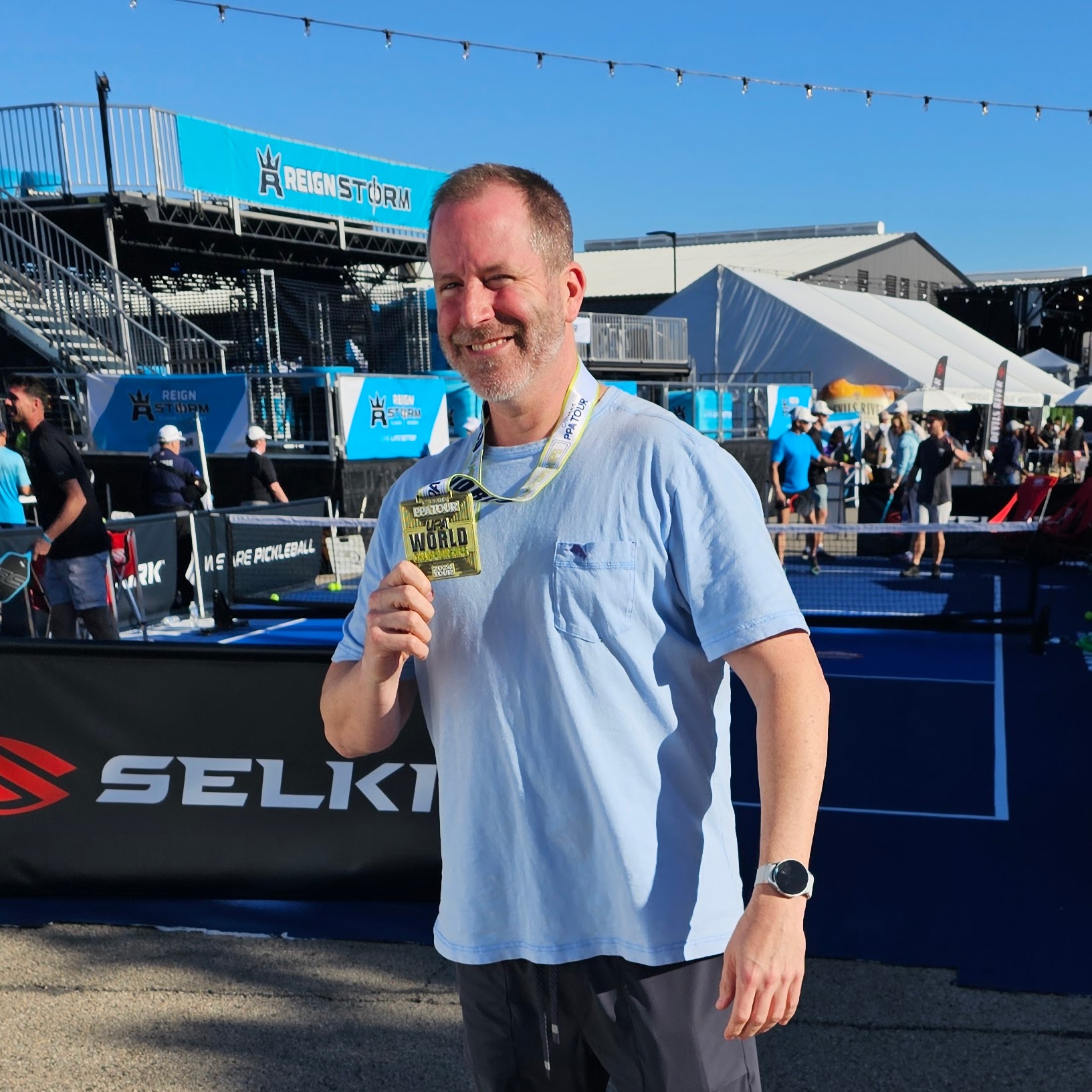 Joshua Whitaker smiling and holding a gold medal at the Reign Storm pickleball event