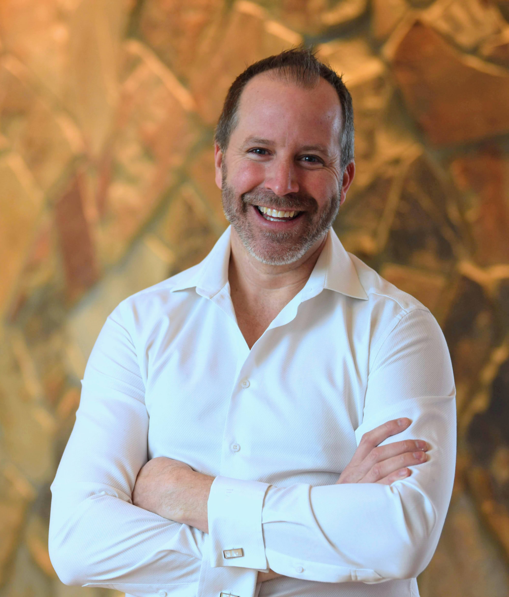 Joshua Whitaker smiling with arms crossed in a white shirt