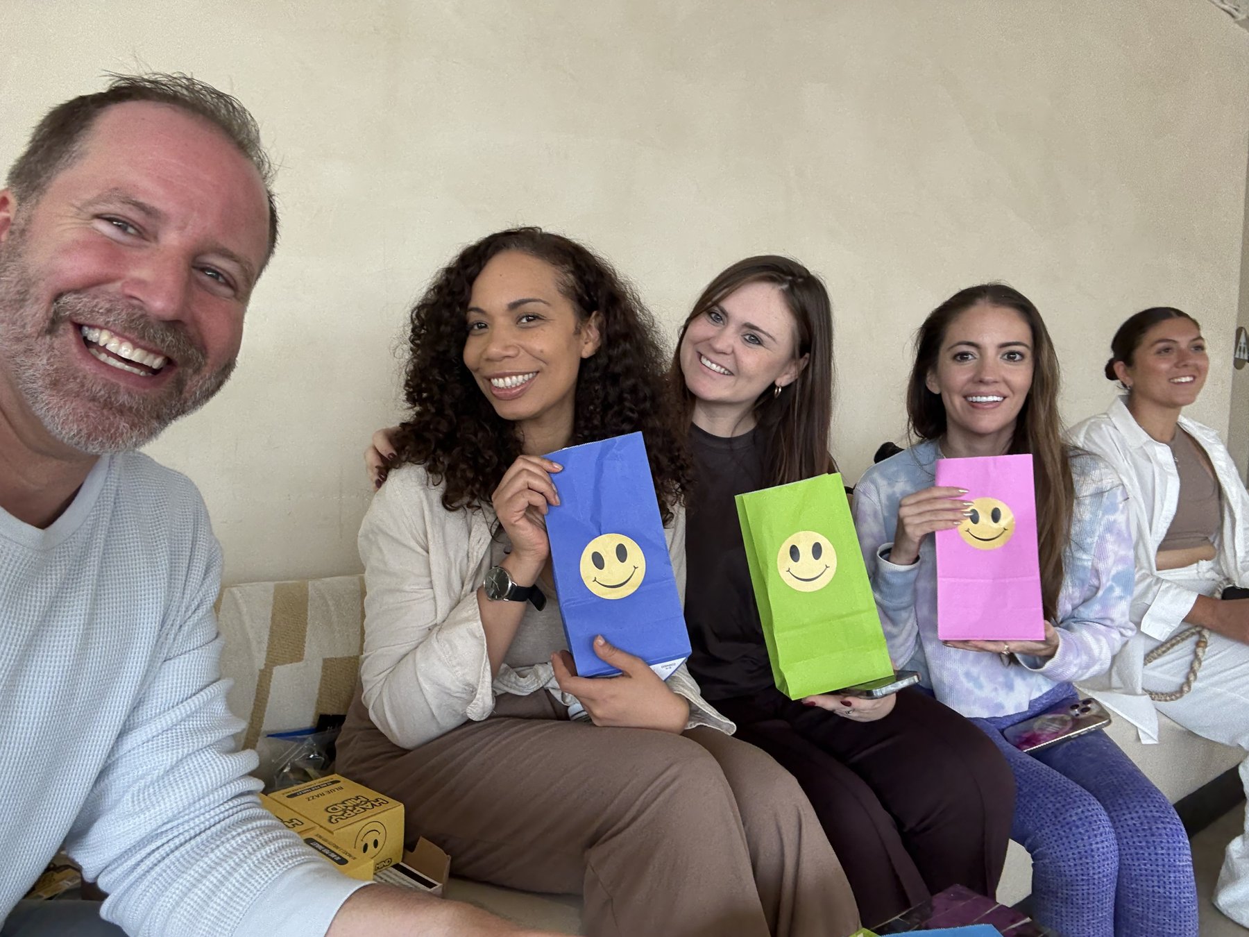Joshua Whitaker smiling with a group holding colorful Happy Mind smiley-face bags